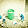 group of miniature humans mopping the floor